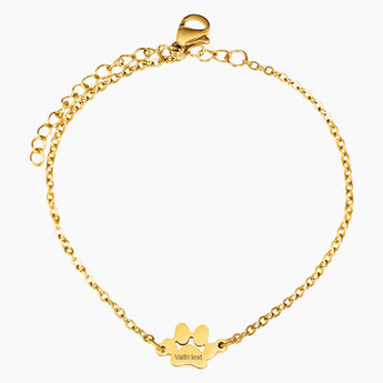 Guldpläterat armband med tassformad berlock med namn graverad i sterling silver mot vit bakgrund