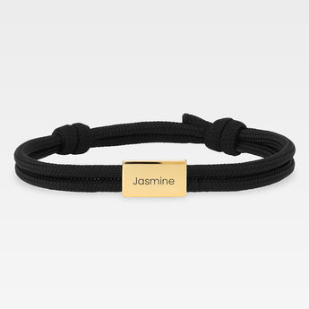 armband med svart snöre och graverad guldbricka med namnet "Jasmine"